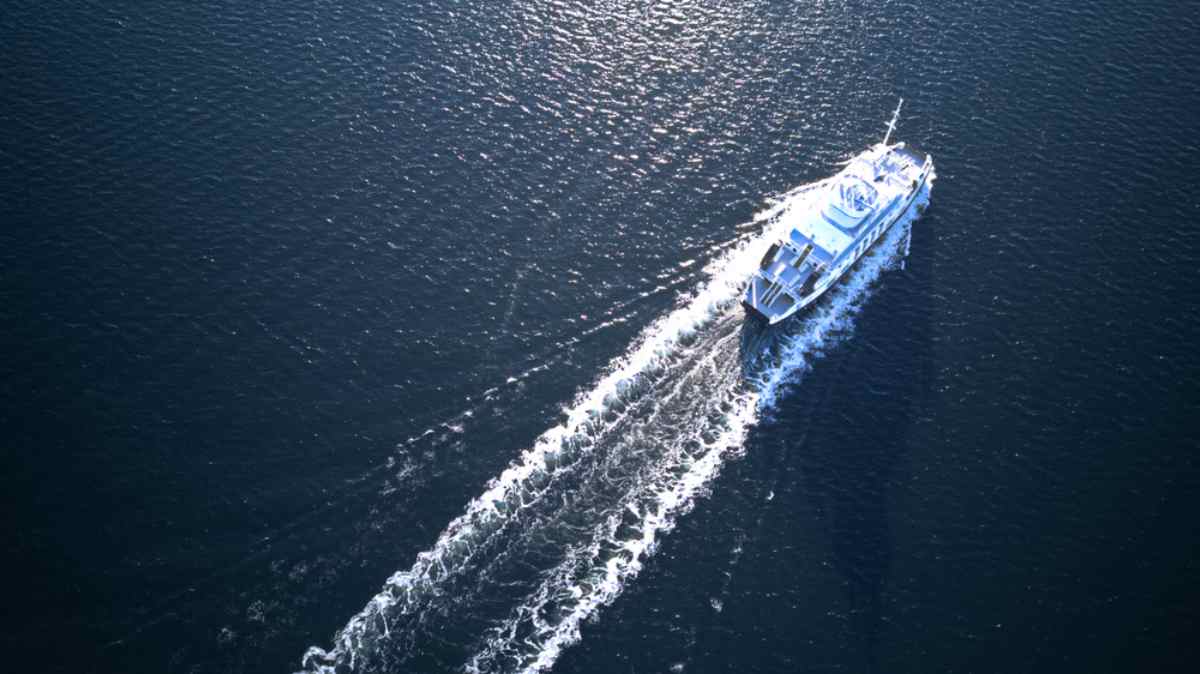 Aerial view of a ferry sailing through the Oslo Fjord, leaving a white wake behind.