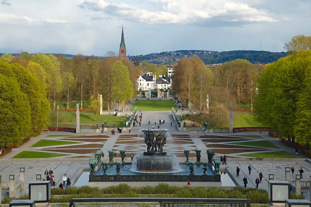 Vigeland Park in Oslo with sculptures, fountain, and tree-lined paths on a spring day.