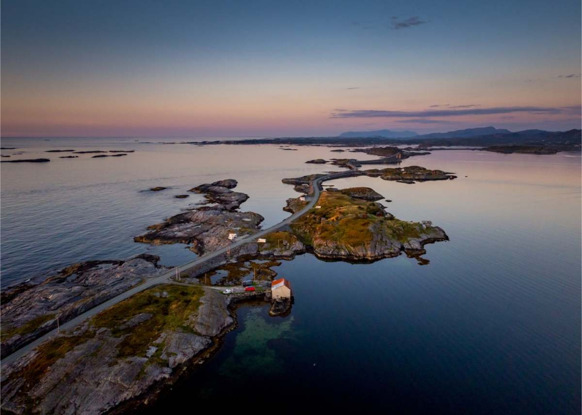 Aerial view of Norway Aerial view of a road linking low rocky islets across calm sea, with a pink and blue sky at twilight
