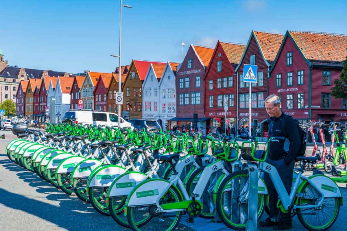 Row of green rental bikes in front of the wooden houses of Bryggen in Bergen.
