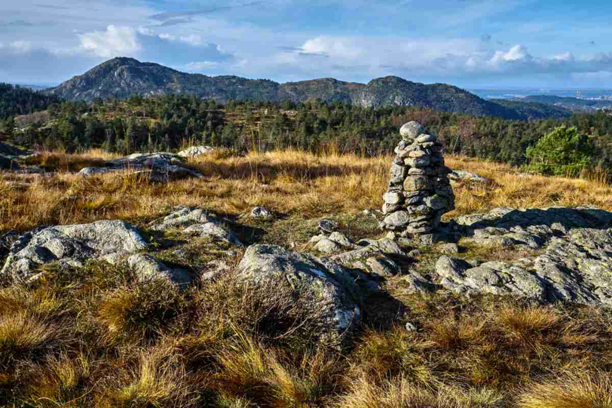 Stone cairn on a hiking trail at Damsgardsfjellet near Bergen, with scenic hills in the background.