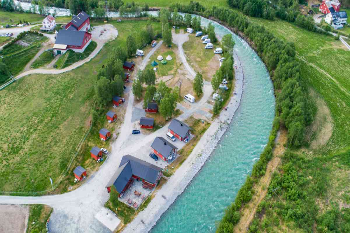 Camping near Jostedalsbreen glacier Aerial view of riverside camping cabins and campervans near Jostedalsbreen in lush green countryside