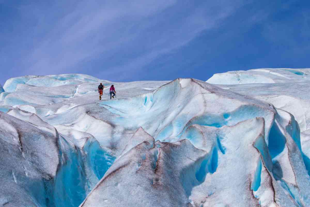 Norway's Nigardsbreen Two hikers walking across bright blue and white ice formations on Jostedalsbreen glacier
