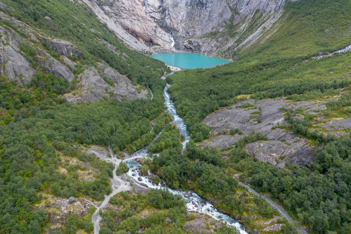 Oldeskaret Trail in Norway Aerial view of hiking trail and river leading to a turquoise glacial lake below Jostedalsbreen