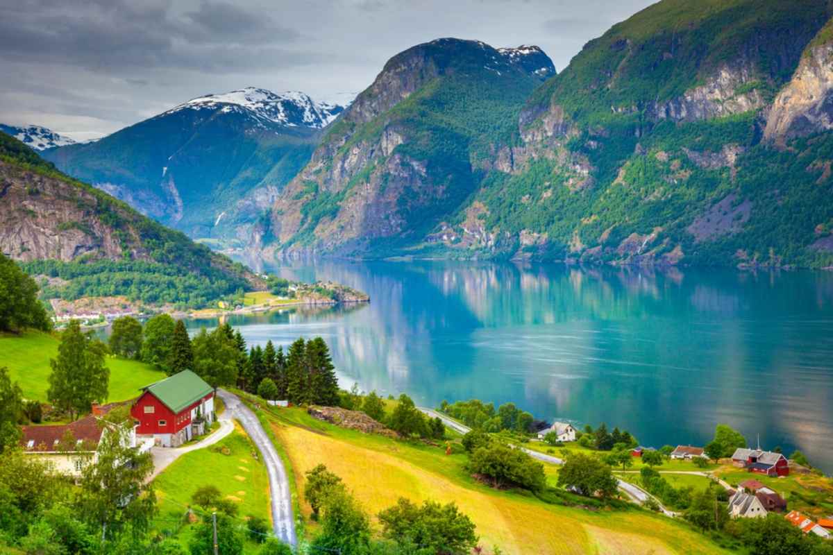 Overview of the Norwegian fjord Sognefjord with its characteristic crystal clear waters and small red wooden cabins surrounding it.