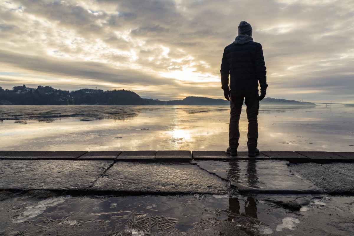 Hamresanden’s long sandy beach Person standing on the waterfront in Hamresanden at sunrise with a dramatic sky