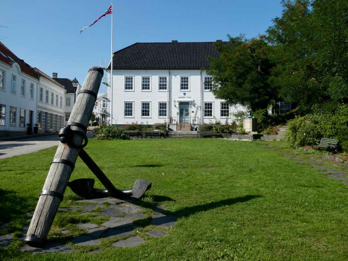 Lillesand town center, Norway Historic white wooden house with a large anchor monument in Lillesand, Norway