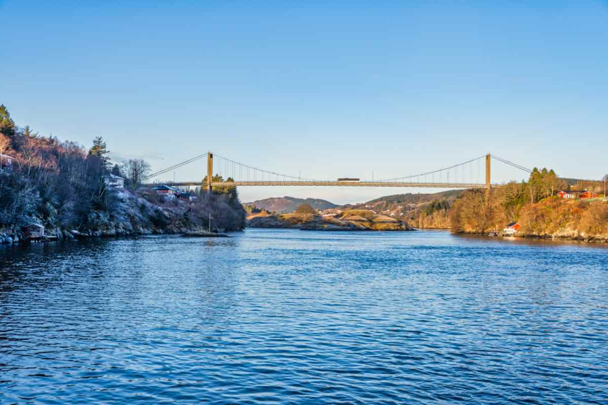 Nordhordland Bridge Suspension bridge crossing a calm fjord between rocky shores, with winter light, blue water, and scattered houses along the coastline.