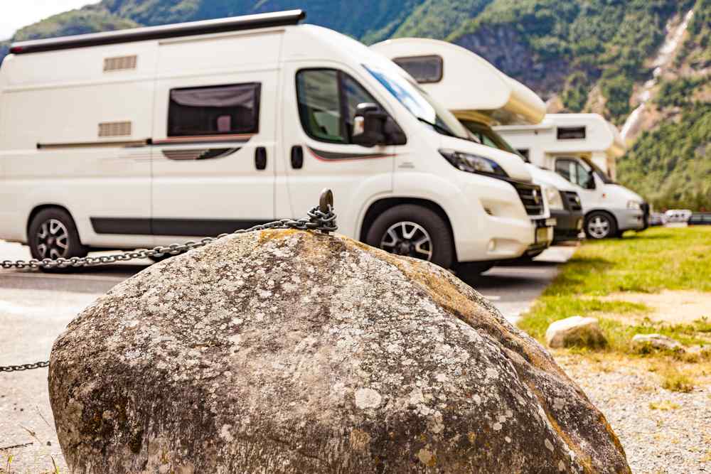 Arriving to Flam, Norway through campervan road trip White motorhomes parked at a campsite in Flåm, Norway, surrounded by steep green mountains.