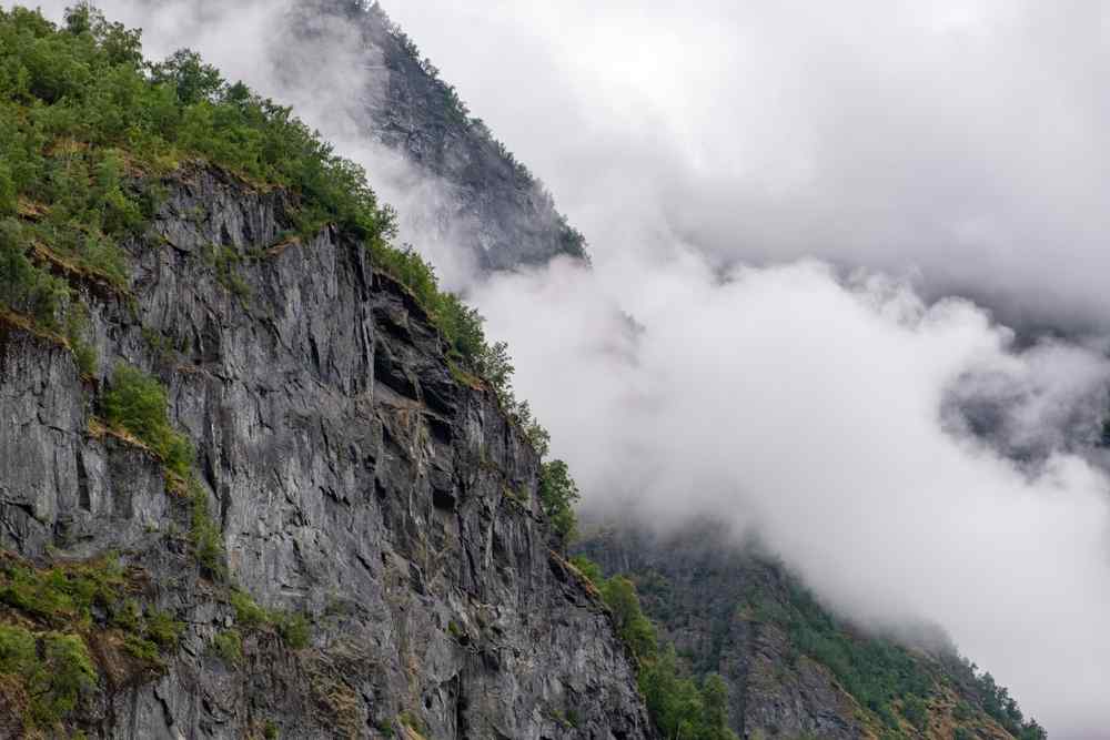 Flam, Norway during shoulder seasons Low clouds drifting across rocky cliffs and forested mountains near Flåm, Norway.