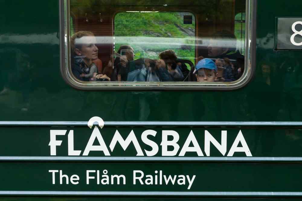 Flamsbana in Flam, Norway Passengers looking through the window of a green Flåm Railway train in Norway.
