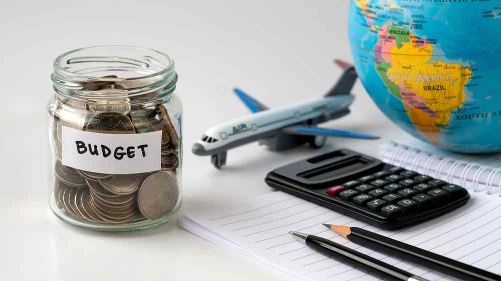 Budget for traveling in Norway Travel budget jar, calculator, model airplane, and globe for planning a five-day Norway trip.